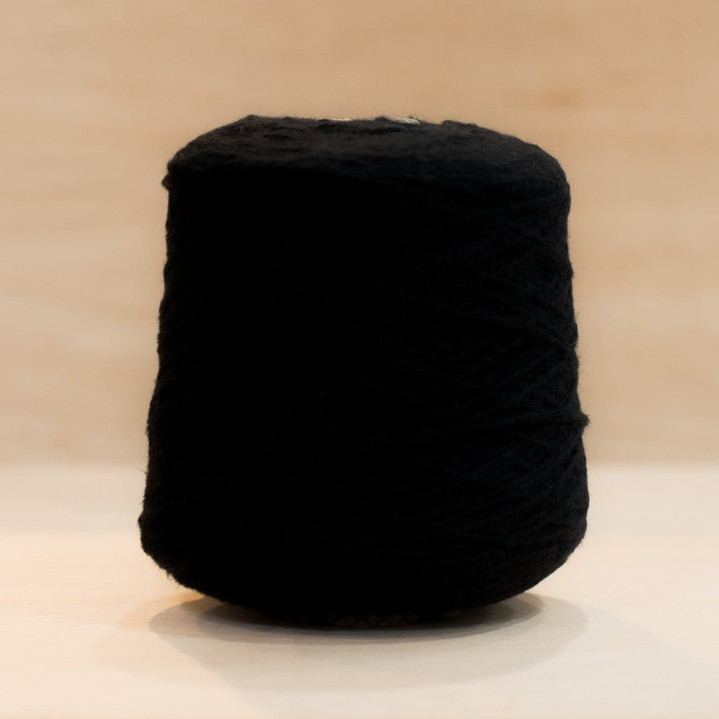 Cheekyarn Loop 8 yarn cone in Asphalt, a deep cool-toned charcoal, against a natural wood background
