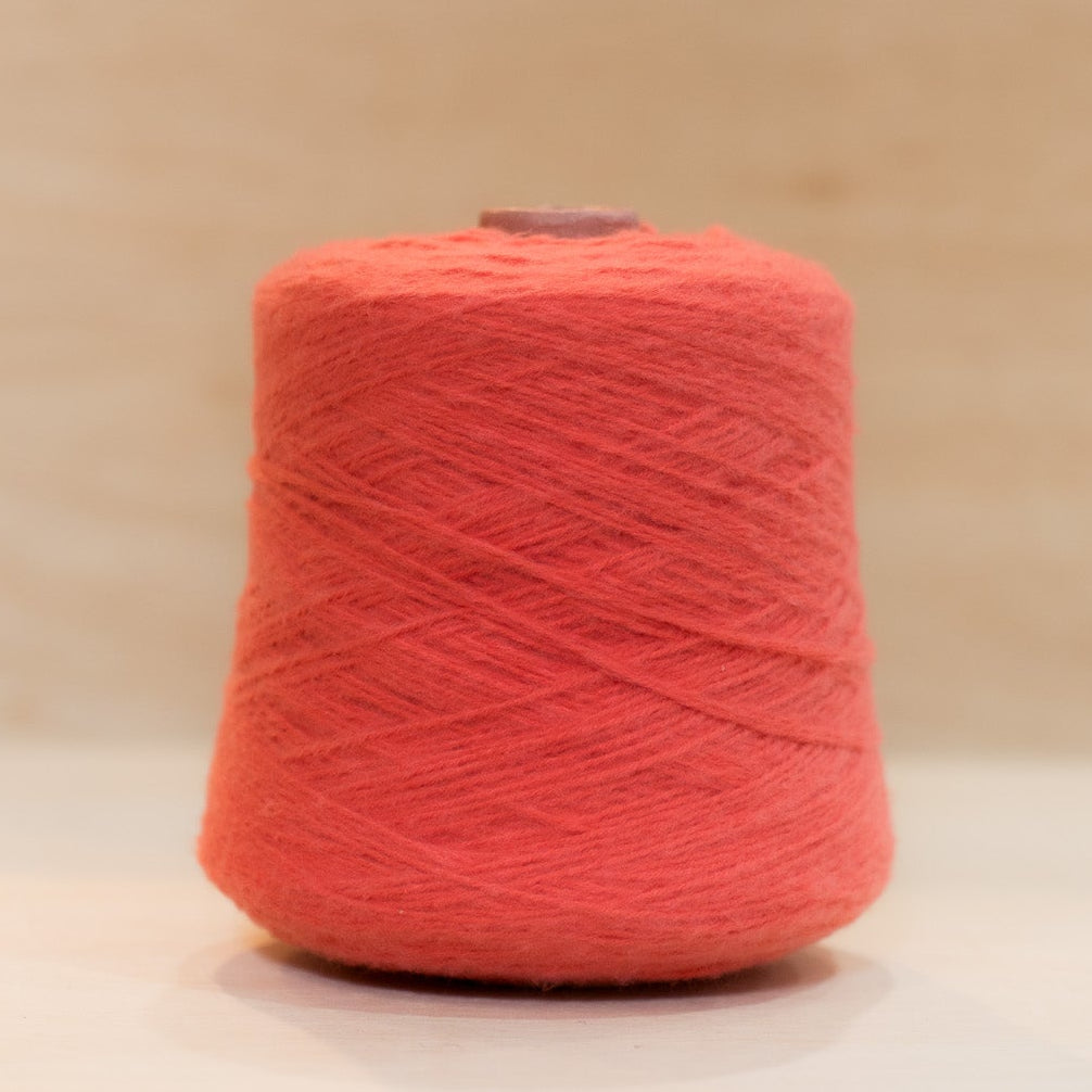 Cheekyarn Loop 8 yarn cone in Bus Stop Ketchup, a warm orange-shifted tomato red, against a natural wood background