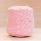 Cheekyarn Loop 8 yarn cone in Chewed Marshmallow, a pale dusty blush pink, against a natural wood background