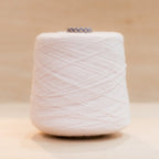 Cheekyarn Loop 8 yarn cone in Hangover Lilac, a pale washed-out grey lilac, against a natural wood background