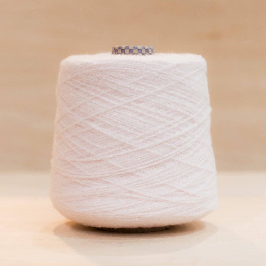 Cheekyarn Loop 8 yarn cone in Hangover Lilac, a pale washed-out grey lilac, against a natural wood background
