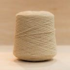 Cheekyarn Loop 8 yarn cone in Tea Biscuit, a warm golden sandy beige, against a natural wood background
