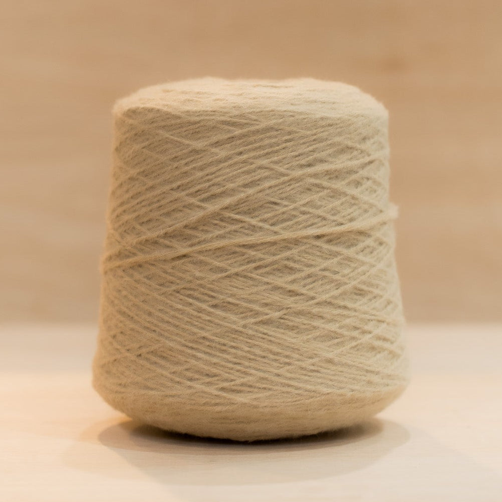 Cheekyarn Loop 8 yarn cone in Tea Biscuit, a warm golden sandy beige, against a natural wood background