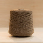 Cheekyarn Loop 8 yarn cone in Sausage Dog, a warm reddish-brown, against a natural wood background