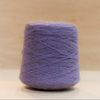 Cheekyarn Loop 8 yarn cone in Royal Bruise, a mid-toned blue-purple, against a natural wood background