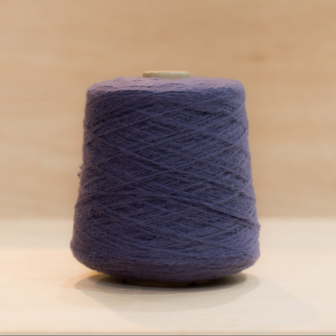Cheekyarn Loop 8 yarn cone in Night Tube, a deep near-black navy-purple, against a natural wood background