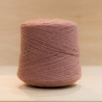 heekyarn Loop 8 yarn cone in Granny Lipstick, a warm faded rose-pink, against a natural wood background