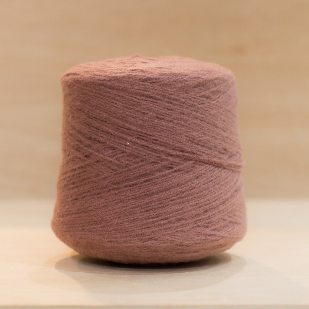 heekyarn Loop 8 yarn cone in Granny Lipstick, a warm faded rose-pink, against a natural wood background