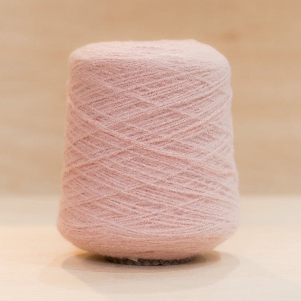 Cheekyarn Loop 8 yarn cone in Ballet Bruise, a dusty muted pink, against a natural wood background