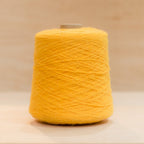 Cheekyarn Loop 8 yarn cone in Taxi Light, a punchy sun-soaked yellow, against a natural wood background
