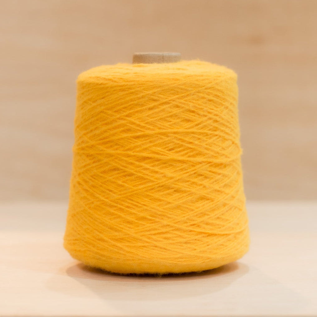 Cheekyarn Loop 8 yarn cone in Taxi Light, a punchy sun-soaked yellow, against a natural wood background
