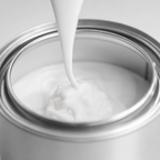 White paint being poured into a silver paint can on a light gray background