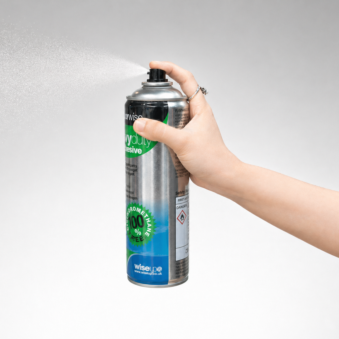 Hand holding a can of Wise 100% Green Cleaning Detergent against a gray background