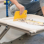 Woman working on a project in a workshop setting with shelves and tools in the background.